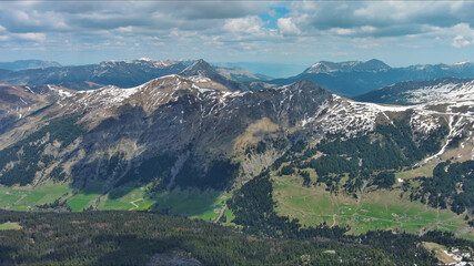 Fototapeta premium Rocky mountains in snow and green fir forest