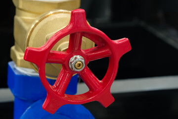 Red and gold valve with a gold stripe. The valve is part of the water supply system pipe