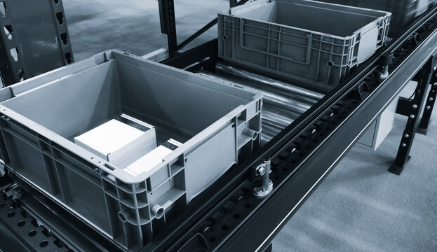 Conveyor belt with two empty plastic containers. Gray containers placed on the conveyor belt. Delivery logistics warehouse storage concept. - Powered by Adobe