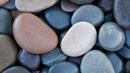 Pebbles stones on seashore as  texture background for design web banner template page. many stones and they are different in color and size, dry stones illuminated by sun