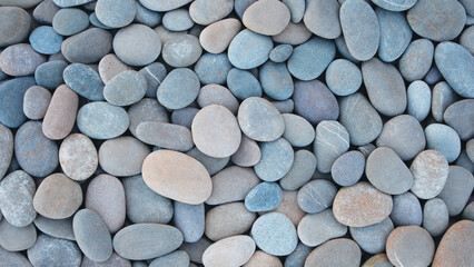 Pebbles stones on seashore as  texture background for design web banner template page. many stones and they are different in color and size, dry stones illuminated by sun