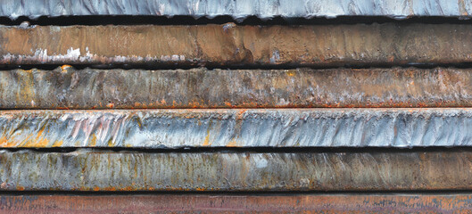 Stack of  thick heavy metal plates rusty uneven surface after laser cutting. plates stacked top each other, creating sense depth and texture. scene is somewhat dark industrial  background