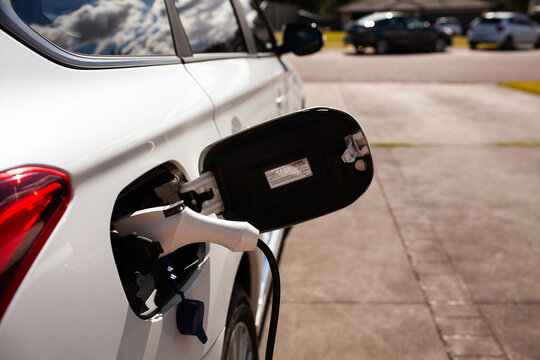 Plugged in Hybrid ev car sitting suburban driveway on charge