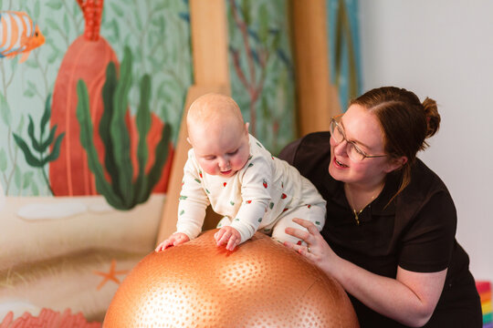 physiotherapist with baby on physio ball doing vestibular stimulation rocking gently