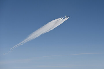 Aeroplane with contrails (condensation trails) or vapour trails; Line-shaped clouds produced by aircraft engine exhaust or changes in air pressure, typically at aircraft cruising altitud