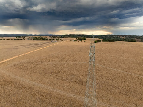 Aerial view of power stanchions in a dry paddock under dark storm clouds at Guildford in Victoria