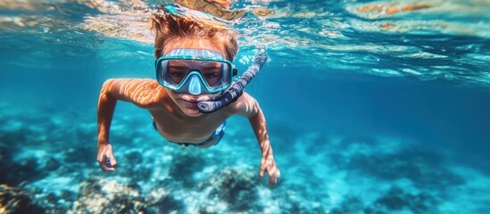 Naklejka premium Boy Swimming Underwater with Snorkel Gear in Clear Turquoise Ocean
