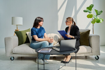 Female patient talking to psychotherapist psychologist, sitting together in office