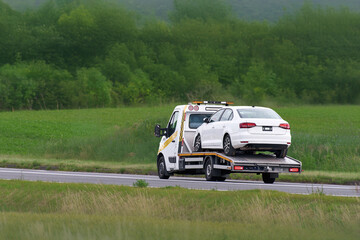 Vehicle recovery truck hauling car after collision