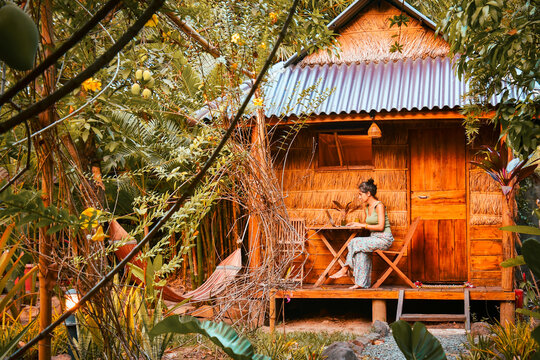 Close up young caucasian hipster woman sit use computer freelance do freelancing work, write travel blog or browse internet search, work online while traveling in southeast asia tropical islands