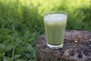 green healthy matcha tea in a transparent glass on a wooden stump
