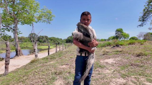 A young Latin boy gently holding a baby giant anteater on a sunny day, in outdoor rural Venezuela, a sweet and touching moment of innocence and wildlife care.
