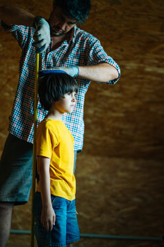 Father measuring child height during home renovation indoors