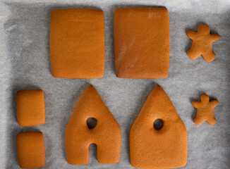 Gingerbread cookies, gingerbread house details on a baking sheet. Christmas eve. Top view.