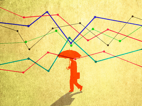 Business person with umbrella walking among volatile financial graphs
