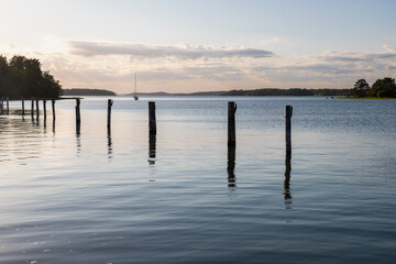 Amazing golden sunset behind the clouds during spring, over the world biggest archipelago near the city Turku seen from the village of Naantali, with calm water and a row of poles for boats to dock 