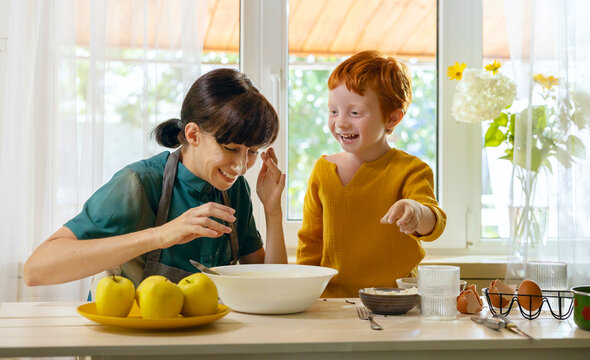 Cheerful boy spending leisure time cooking with mother in kitchen