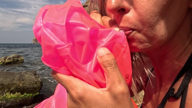 Woman inflating beach float, summer vacation preparation by the sea