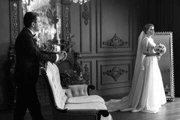young couple bride and groom in a dark studio with a floor mirror