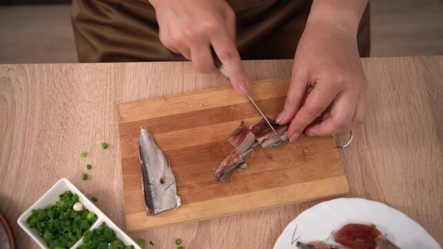 cut fillets of salted herring on wooden board