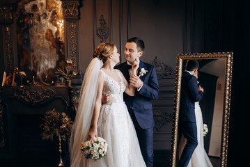 young couple bride and groom in a dark studio with a floor mirror