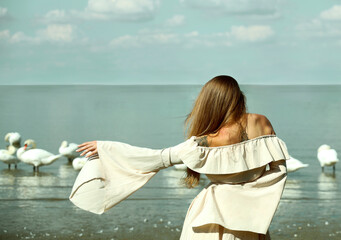 meeting between flock swans and back rear view of young elegant tattooed girl female woman wear...