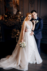 young couple bride and groom in a dark studio with a floor mirror