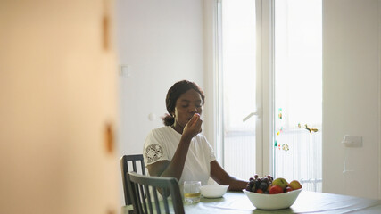 Casual Kitchen Scene: African Woman Enjoying Muesli at the Table..
