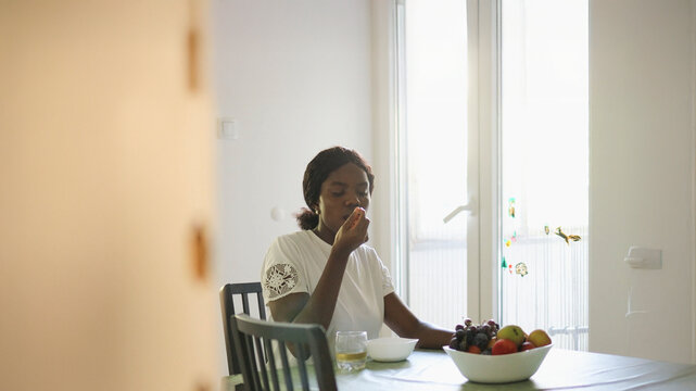 Casual Kitchen Scene: African Woman Enjoying Muesli at the Table..