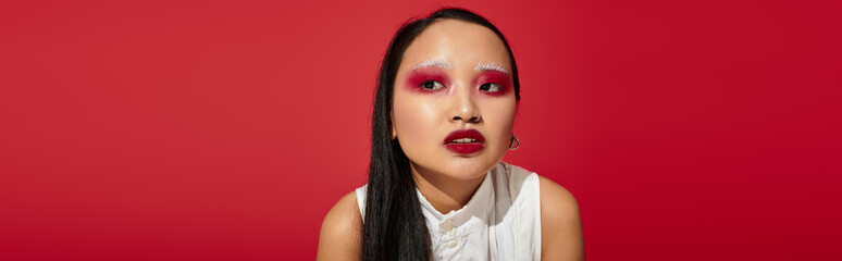 Vibrant beauty shines in red studio showcasing stylish makeup and trendy outfit