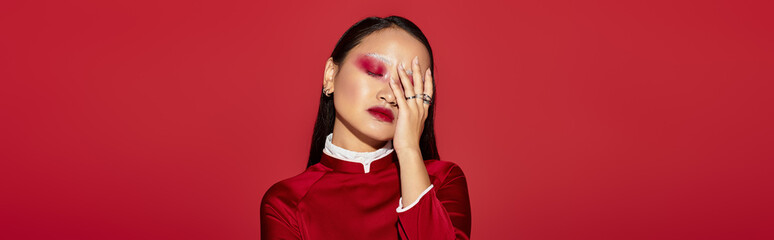 Vibrant eye makeup and stylish outfit showcase beauty in a striking red studio setting