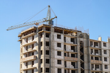 Urban residential tower with crane under construction. Large apartment tower building with crane, under development. Represents housing growth, investment, and construction progress.