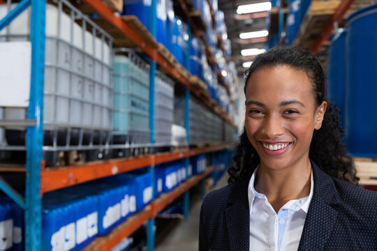 Industrial warehouse aisle stretching into distance, holding blue barrels and grey IBC containers