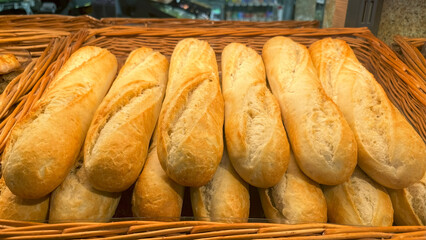 Fresh baguettes, arranged in a woven basket straight from the oven, are ready for sale.