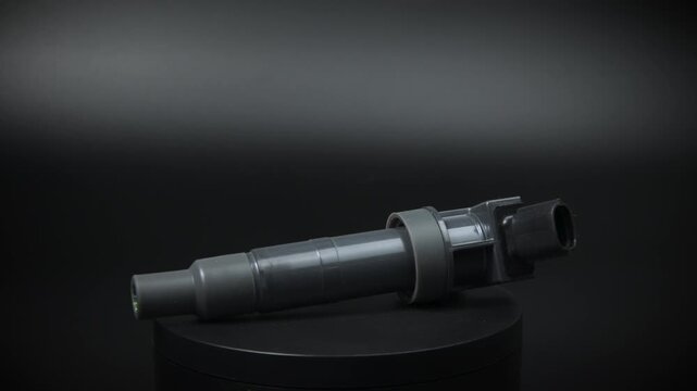 New ignition coil of internal combustion engine rotates on black background. New engine parts