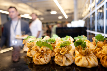 Stuffed pastry pouches with lettuce on buffet table catering at business event.