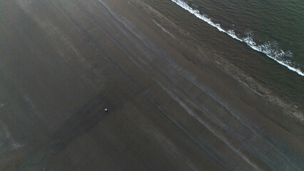 Aerial top-down shot of Miramar Beach in Goa during winters, highlighting detailed sand textures and gentle sea waves along the scenic coastline.