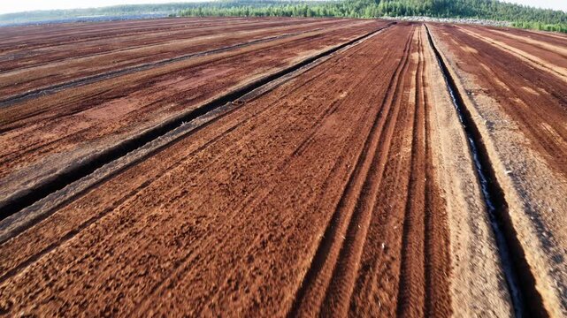 Drone flight forward. Aerial view of peat extraction bog. Large peat extraction field.