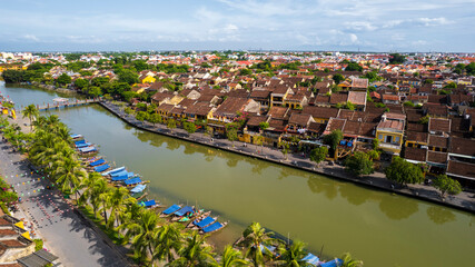 a peaceful view of Hoi An's historic riverside, with its charming yellow-walled buildings and traditional tiled roofs reflecting on the calm Thu Bon River. © Nhan