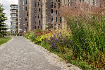A scenic view of a modern urban park with colorful flower beds and a paved path, inviting visitors to explore