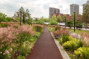 A vibrant pathway surrounded by colorful flowers in a modern urban park, inviting nature lovers and walkers to enjoy the serene atmosphere