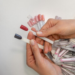 A nail technician showcasing a variety of nail polish colors on swatches, highlighting the latest trends in nail artistry