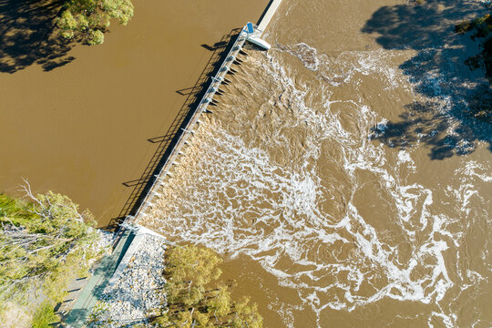 Aerial view of a river weir with foaming water cascading downstream