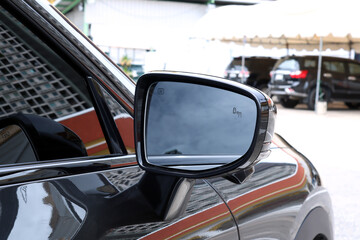 Fototapeta premium close up view of a modern black electric ev car side mirror with clear reflection, showcasing details of automotive exterior design, safety feature, and transportation concept in an urban environment