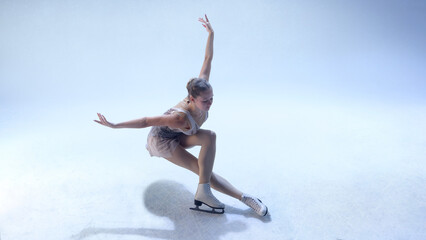 Fototapeta premium Figure skater bending low in dynamic choreographic move on white ice. Concept of fitness power, movement art, editorial performance, and lifestyle inspiration.