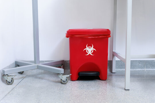 Medical waste disposal room with red biohazard containers and bins