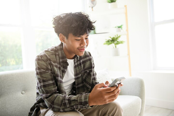 thai teen using cellphone at home sofa