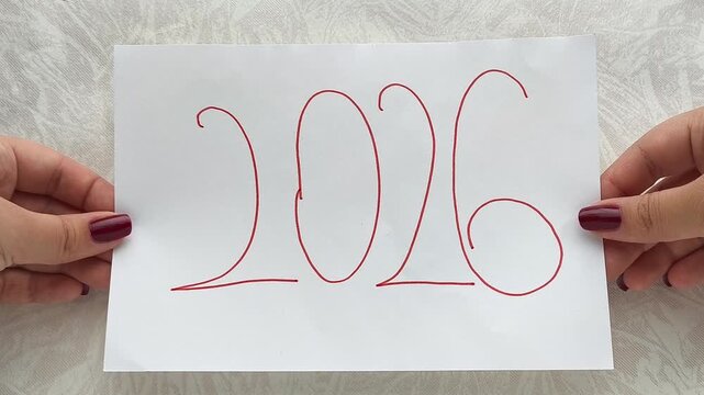 A woman holds a white A4 sheet that says 2026. The concept of goals and plans for the new year.