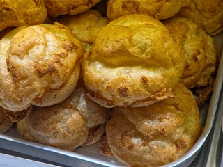 A pile of freshly baked cream puffs or Choux à la crème in a metal tray.