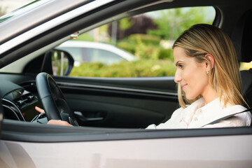 Naklejka premium Businesswoman driving electric car selecting music on dashboard touchscreen